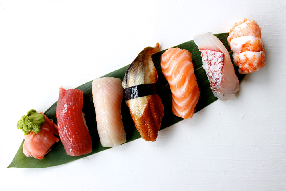 A delicious serving of various types of sushi served on a leaf from Atlanta Fish Market